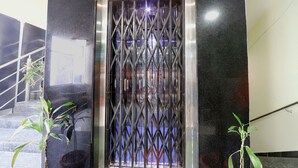 A metal gate with a geometric pattern, a staircase with a handrail, and two potted plants. - FabHotel Galaxy Suites (Hyderabad)