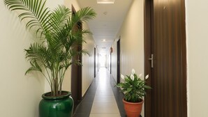 A hotel hallway with a green plant on the left and a potted plant on the right. - FabHotel Galaxy Suites (Hyderabad)