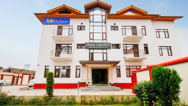 A multi-story hotel with a prominent 'fab hotels' sign, a 'Grand Comforts' sign, and a symmetrical facade with balconies. - Fabhotel Grand Comforts (Srinagar)