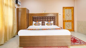 A bedroom with a large bed, a wardrobe, a door, and a red patterned rug. - Fabhotel Grand Comforts (Srinagar)