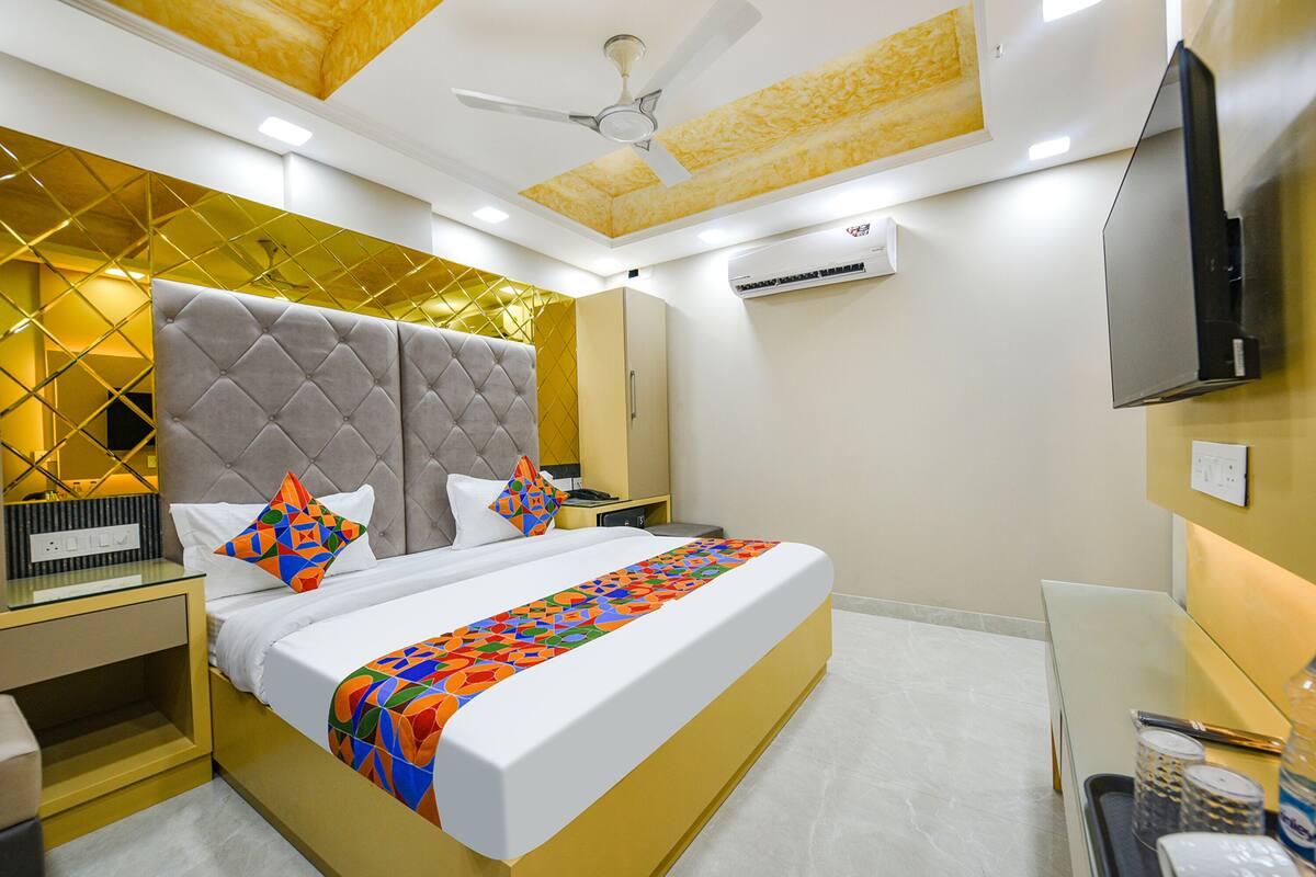 Une chambre d’hôtel moderne dotée d’un grand lit, d’un ventilateur de plafond, d’un appareil de climatisation et d’un téléviseur à écran plat.