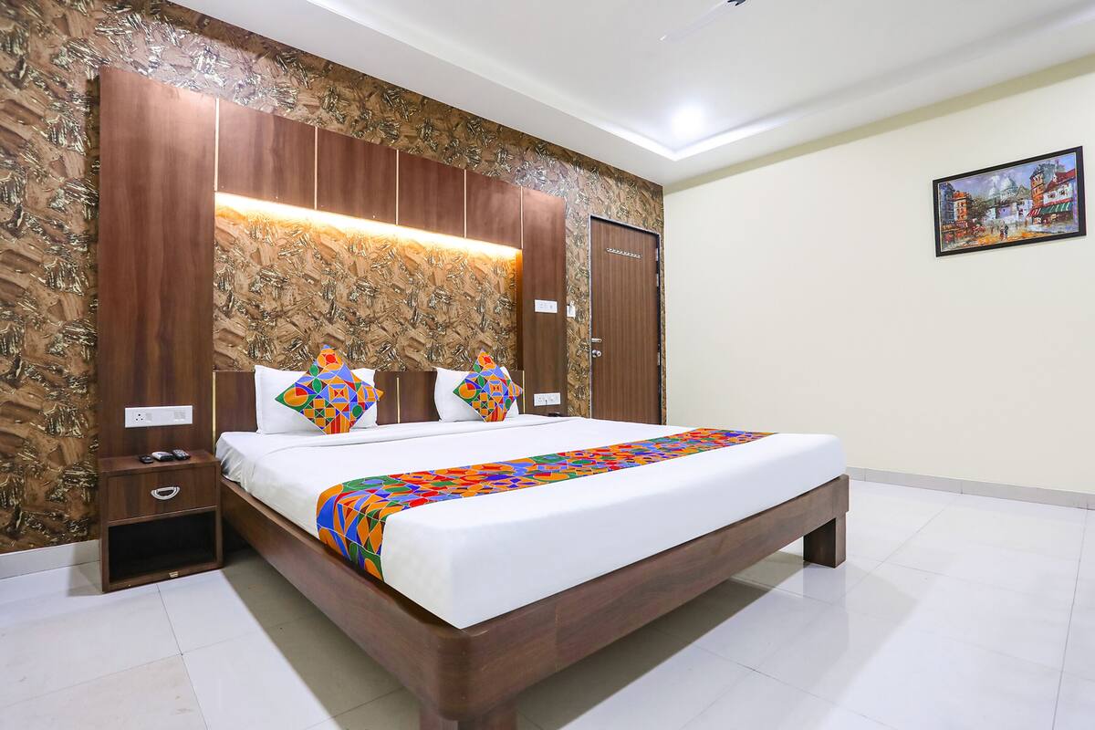 A bedroom with a wooden bed, a nightstand, a bedside table, and a wall-mounted shelf.