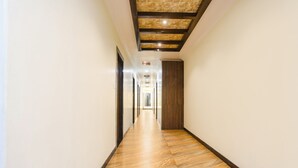 A long, narrow hallway with wooden flooring and a ceiling with exposed beams and recessed lighting. - Fabhotel Heritage I (Durg)