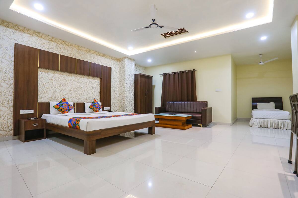 A modern bedroom with a large bed, a desk, a sofa, and a ceiling fan.