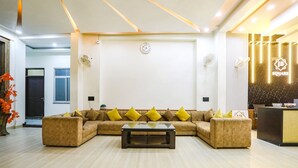 A modern living room with a sectional sofa, a coffee table, and a reception desk. - Fabhotel Jb Square Resort (Faizabad)
