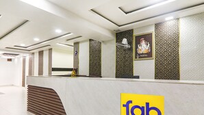 A reception area with a modern design, featuring a reception desk, patterned wall decorations, and a logo for 'fab hotels'. - Fabhotel Keshri Inn (Prayagraj)