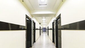 A long, narrow hallway with doors on both sides, leading to a blue-lit room at the end. - Fabhotel Keshri Inn (Prayagraj)