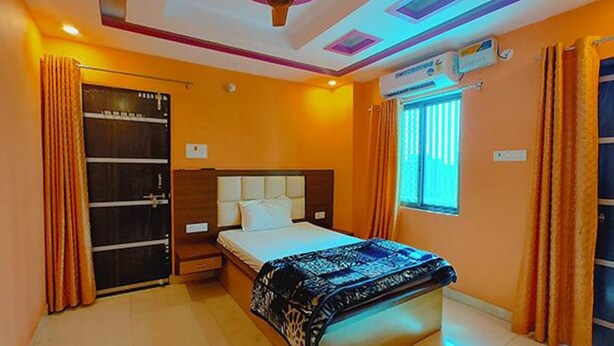 A bedroom with a bed, a nightstand, a wardrobe, and a window with curtains. - Fabhotel New Raghukul Loung (Faizabad)