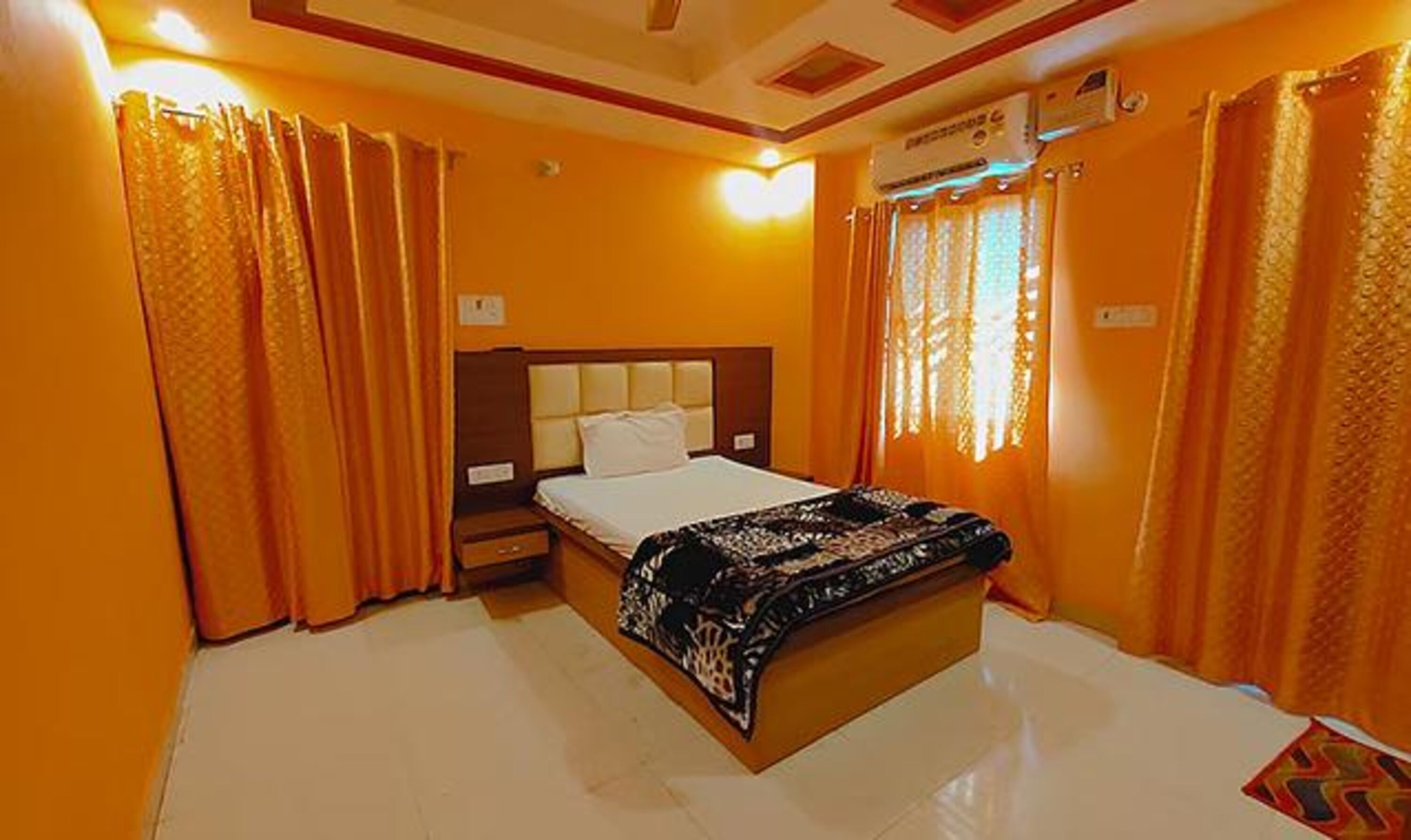 Une chambre d’hôtel avec un lit, une table de chevet, un appareil de climatisation et des rideaux.