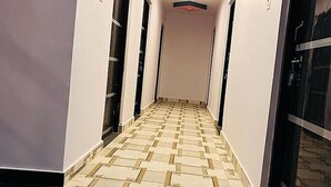 A hallway with patterned flooring, white walls, and doors on either side. - Fabhotel New Raghukul Loung (Faizabad)