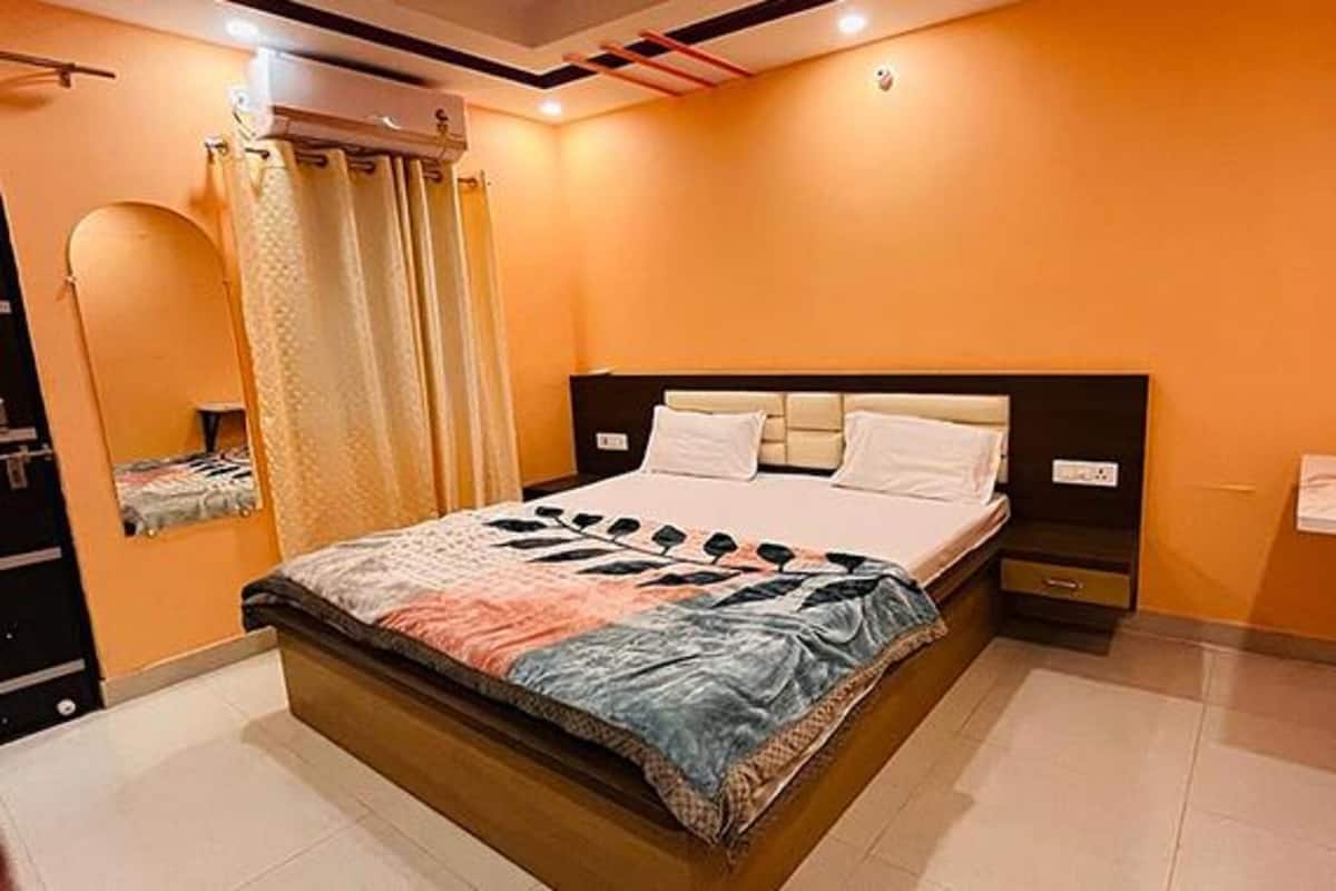 A bedroom with a bed, a nightstand, a mirror, and a window with curtains.