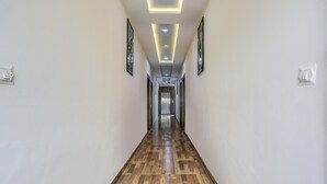A hallway with wooden flooring, recessed lighting, and framed artwork on the walls. - Fabhotel Orchid (Agra)