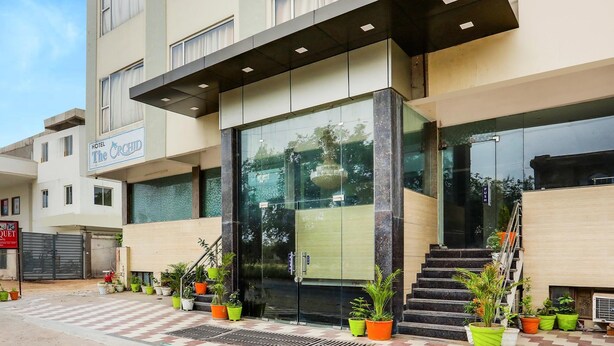 A hotel entrance with a glass facade, a sign reading "The Orchid," and a staircase leading to the entrance. - Fabhotel Orchid (Agra)