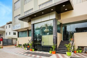 A hotel entrance with a glass facade, a sign reading "The Orchid," and a staircase leading to the entrance.