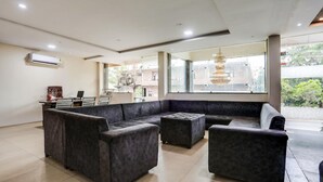 A modern living room with a sectional sofa, ottoman, and a large window providing natural light. - Fabhotel Orchid (Agra)