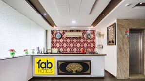 A reception desk with a clock, air conditioning unit, and a framed picture. There is a sign for 'fab hotels' and a reception area. - Fabhotel Orchid (Agra)