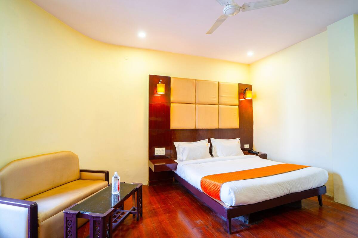 Une chambre d’hôtel avec un lit, un canapé, une table de chevet et une table.