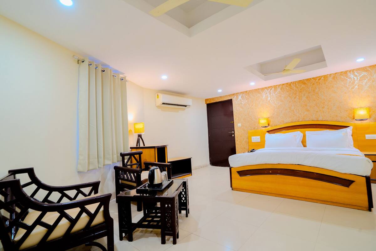 Une chambre d’hôtel comprenant un lit, un bureau avec une chaise, une table et un ventilateur de plafond.