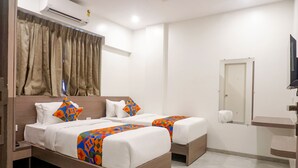 A hotel room with two beds, a wooden headboard, a mirror, and a small bathroom area. - Fabhotel Prime Athiti Delight Stay (Pune)
