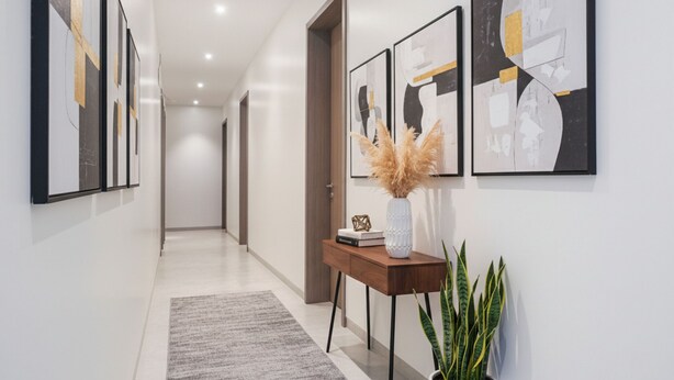 A hallway with abstract art on the walls, a wooden console table with a vase and a plant, and a gray rug on the floor. - Fabhotel Prime Athiti Delight Stay (Pune)