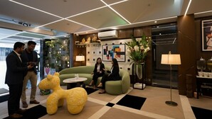 Eine moderne Lobby mit einem grünen Sofa, einer großen, gelben Skulptur und einem Couchtisch.