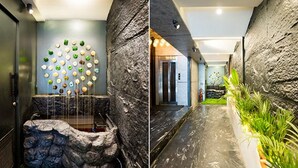 Ein modernes Interieur mit einer Steinwand, einem Wandkunstwerk und einem Empfangsbereich mit Steinwand und Pflanze.