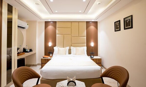 Ein Hotelzimmer mit einem großen Bett, zwei Nachttischen, einem Schreibtisch und zwei Stühlen.