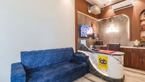 A hotel reception area with a blue sofa, a marble reception desk, and a television mounted on the wall. - Fabhotel Raj Palace (Lucknow)
