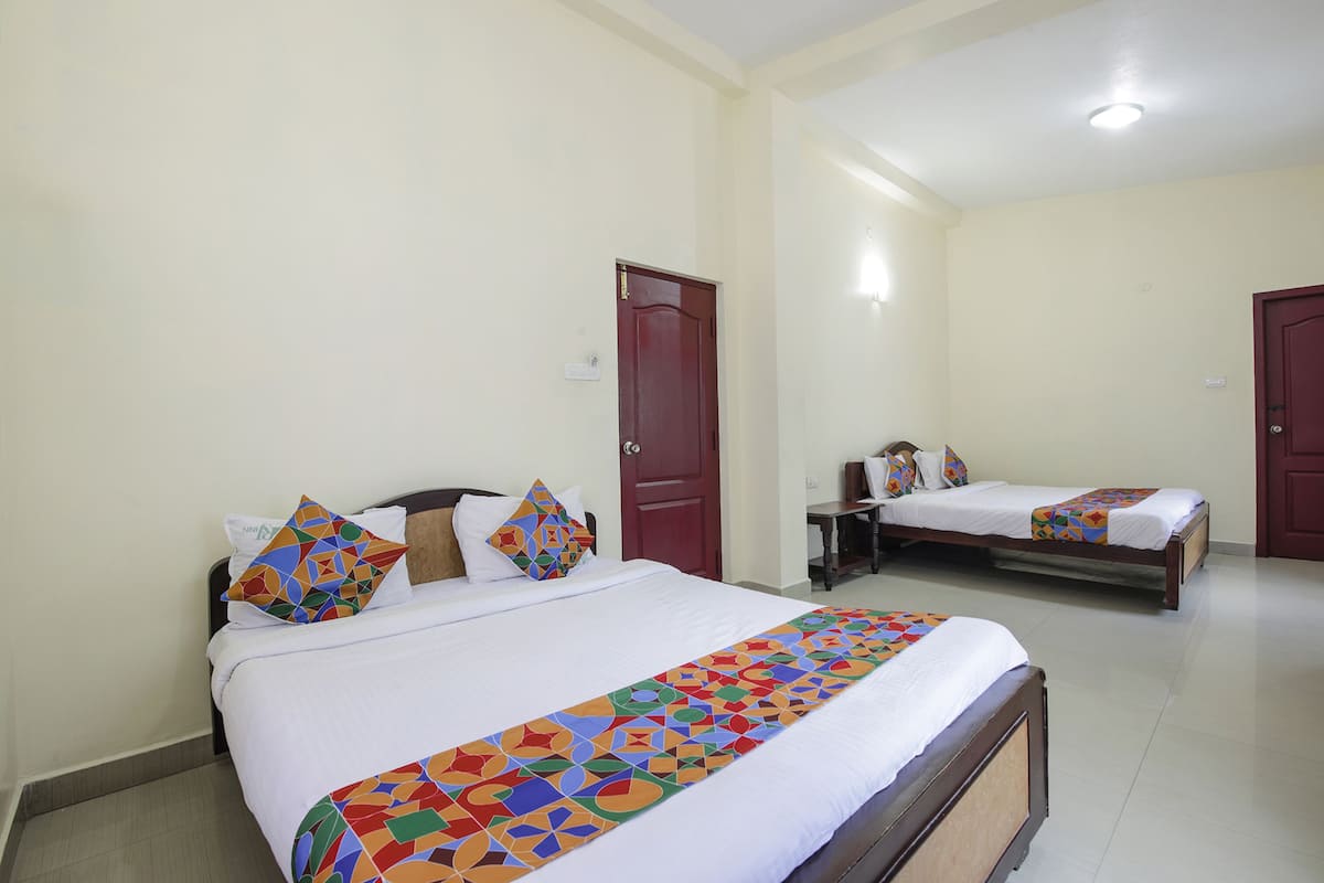 Ein Hotelzimmer mit zwei Betten, einem Holzkopfteil, einer roten Tür und einer weißen Wand.