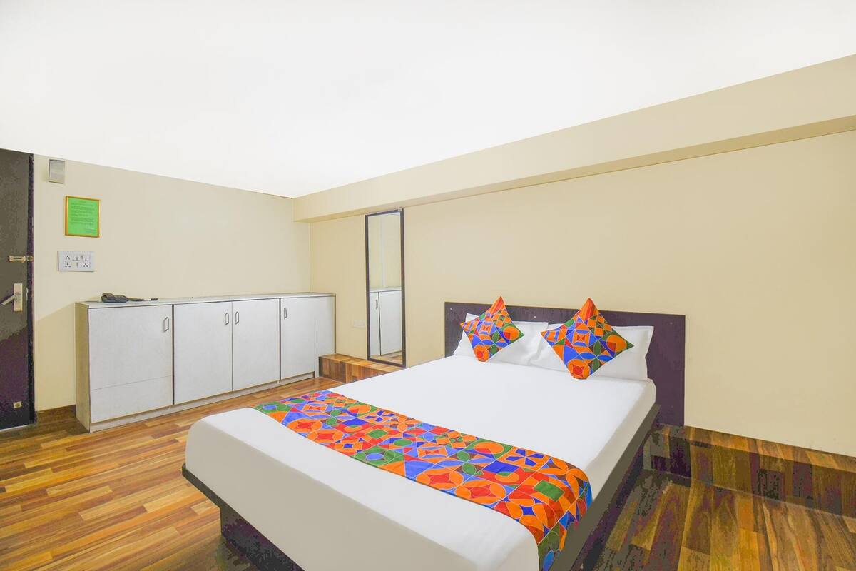 A hotel room with a large bed, a wardrobe, a mirror, and a wooden floor.