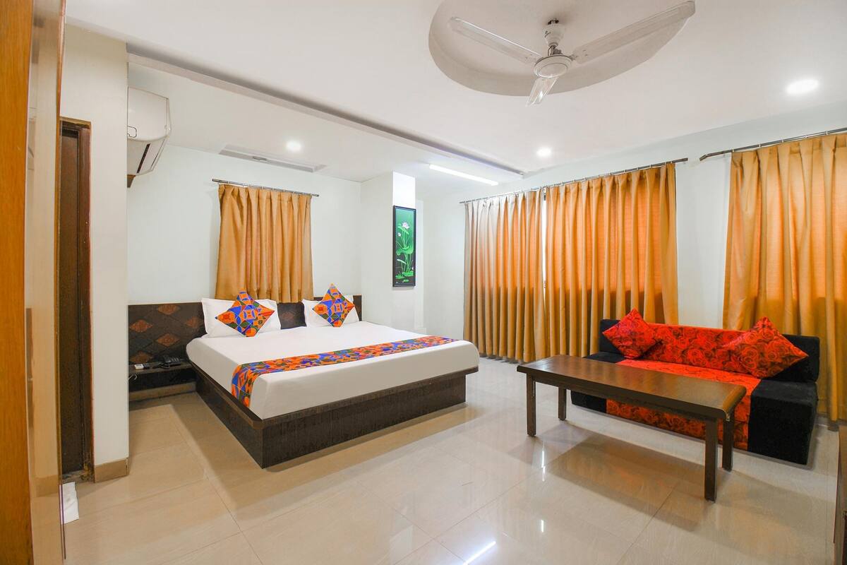 A hotel room with a bed, a sofa, a table, and curtains.
