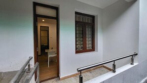A staircase with a metal handrail leading to a landing. A window with a wooden frame and glass panels is visible on the landing wall. - Fabhotel Sri Vari Studio Apartment (Kodaikanal)