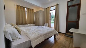 A bedroom with a bed, a wardrobe, and a door leading to a balcony. - Fabhotel Sri Vari Studio Apartment (Kodaikanal)