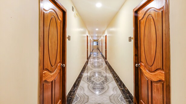 A corridor with wooden doors and a patterned floor. - Fabhotel Sun Lux Grand Residency (Vanur)