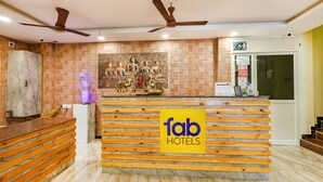 A reception desk with a 'fab hotels' sign, a mural of seated figures, and a ceiling fan. - Fabhotel Sun Lux Grand Residency (Vanur)