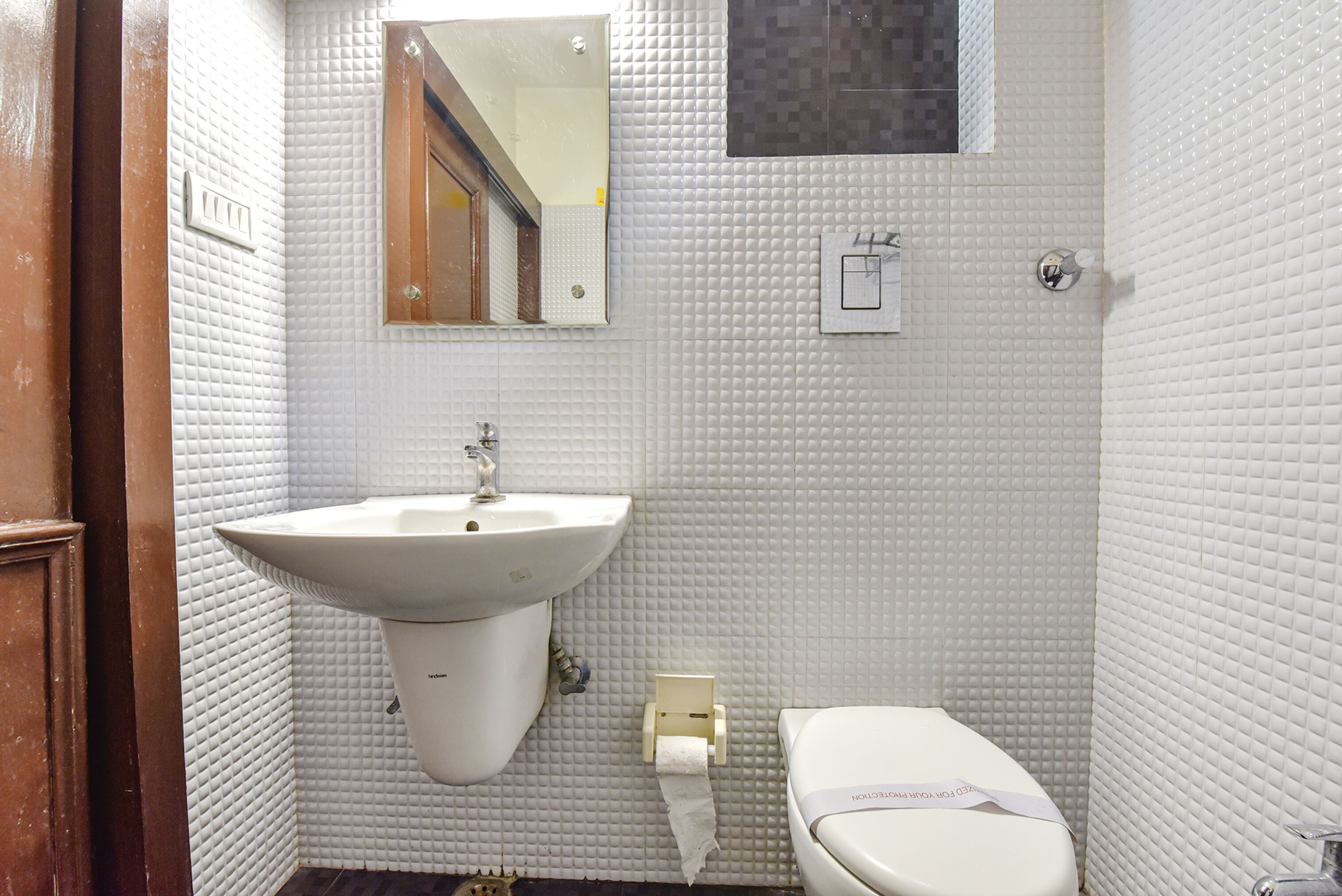 Un baño pequeño con lavamanos, inodoro y espejo blancos.