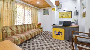 A reception area with a sofa, a reception desk, and a sign that reads "fab hotels". - Fabhotel The Legend Residency (Srinagar)