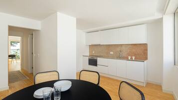 A modern kitchen with white cabinets, a granite countertop, and a black dining table with four chairs.