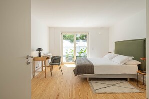 Una camera da letto con un letto, una scrivania, una sedia e vista sul verde.