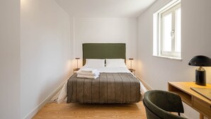 Un dormitorio con cama, lámparas de noche, escritorio y una silla.