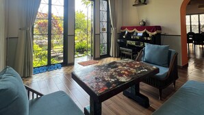 Een ruime woonkamer met een groot raam, een piano en een bank.