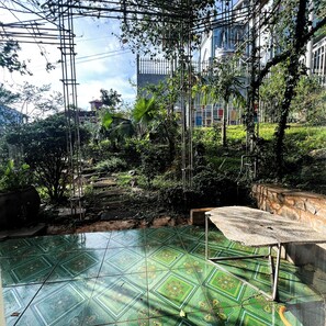 A room with a patterned green floor, a metal frame structure, and a view of buildings in the background.