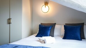 A neatly made bed with a blue blanket, a white towel, and a pair of slippers. - Torino Centro, Il Principino (Torino)