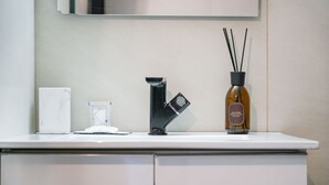A modern bathroom with a white countertop, a black faucet, a white tissue box, and a bottle of reed diffuser. - Torino Centro, Il Principino (Torino)
