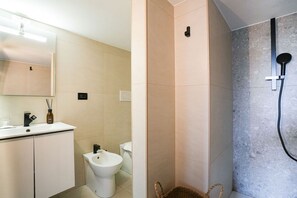 Un baño moderno con lavamanos, inodoro y zona de ducha.