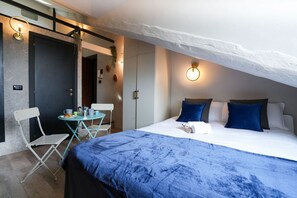 Un dormitorio con una cama grande, una mesita con sillas y una puerta que da a otra habitación.