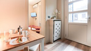 A compact kitchen with a wooden table, a small refrigerator, and a TV mounted on the wall. - Torino Centro, Gioberti Suite (Torino)