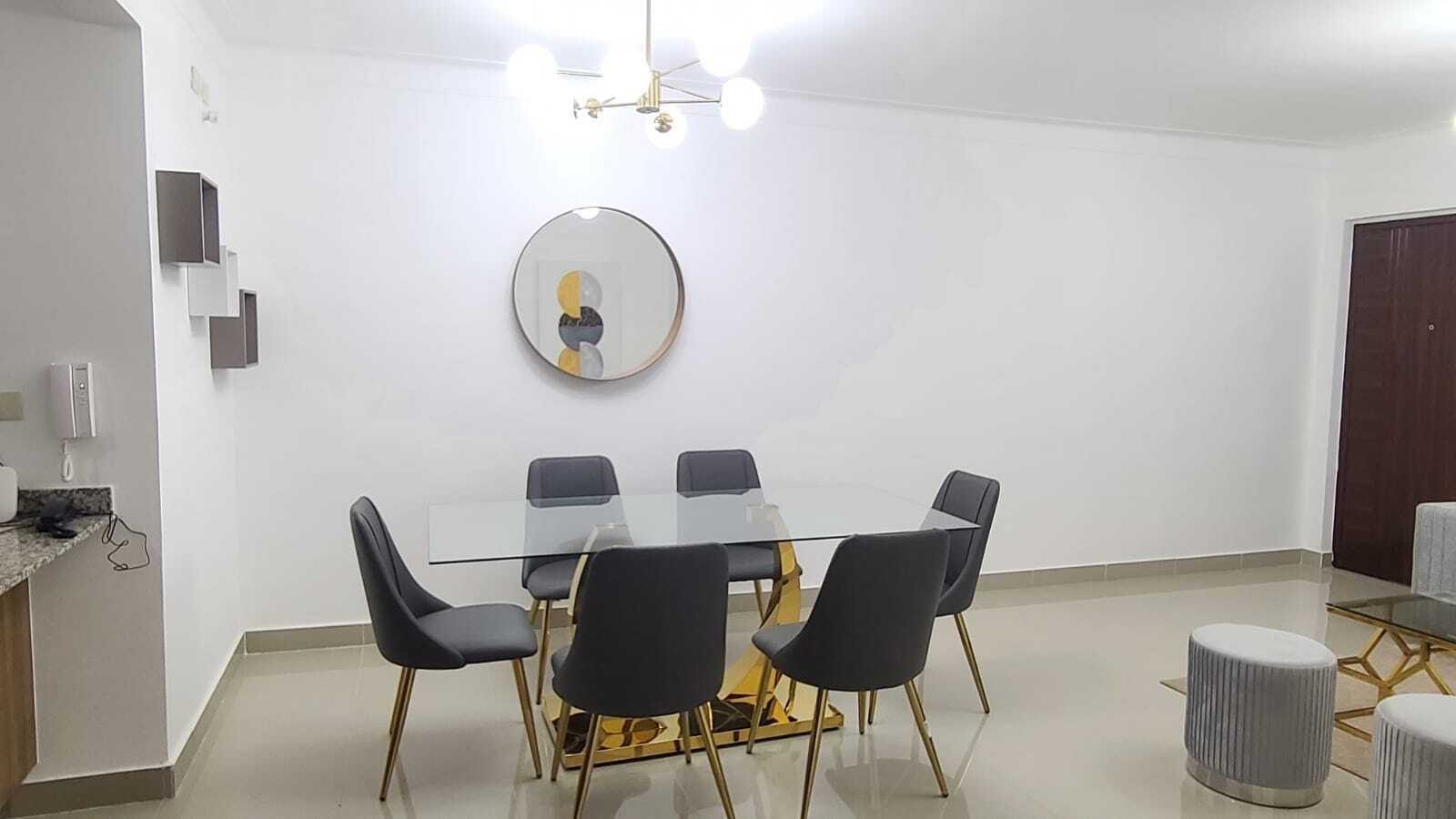 A modern meeting room with a glass table, black chairs, and a gold base.