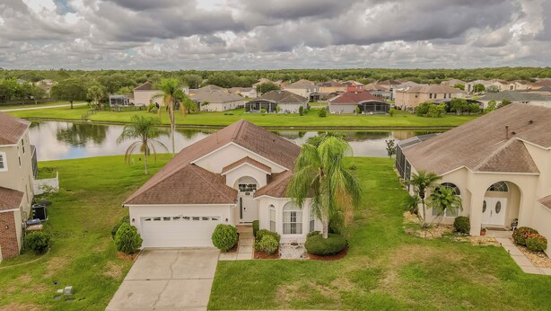 A residential area with houses, a lake, and a well-maintained lawn. - Spectacular Oasis + Pool + Games + Pet friendly (Kissimmee)
