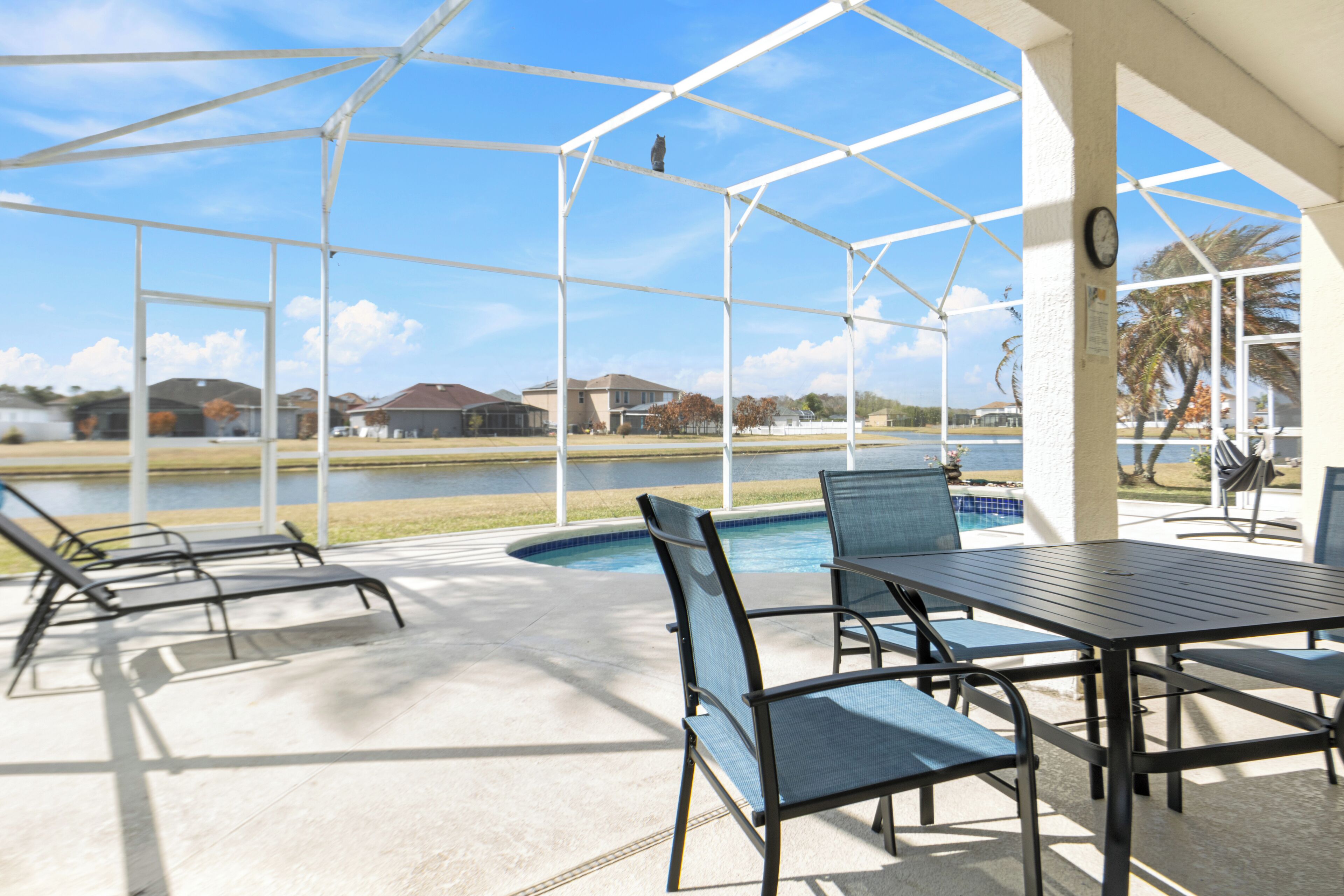 A covered outdoor area with a pool, lounge chairs, and a table.